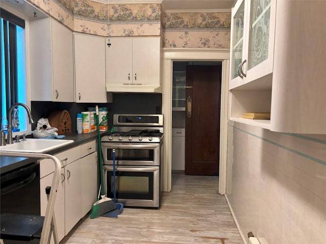 kitchen featuring a sink, under cabinet range hood, range with two ovens, light wood-type flooring, and black dishwasher