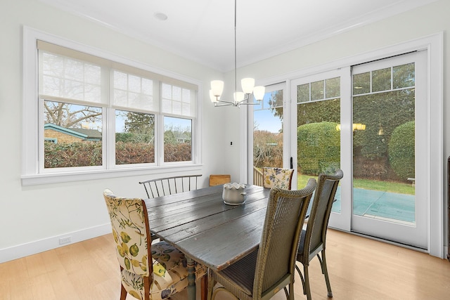 dining room featuring ornamental molding, light wood-type flooring, and a notable chandelier