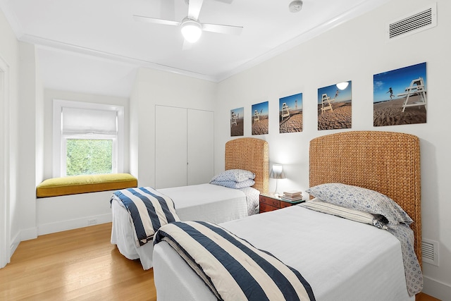 bedroom featuring hardwood / wood-style flooring, ceiling fan, crown molding, and a closet