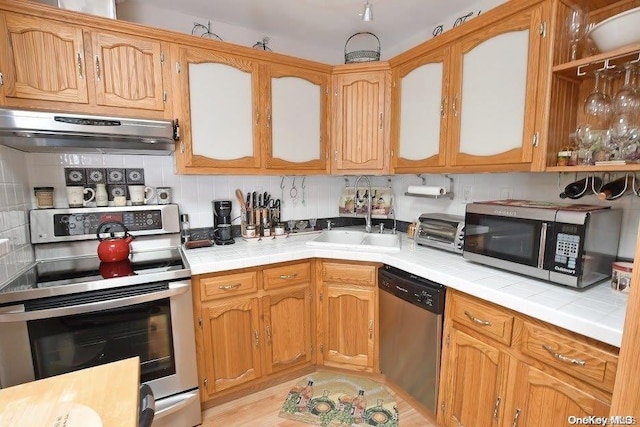 kitchen with backsplash, tile counters, stainless steel appliances, and sink