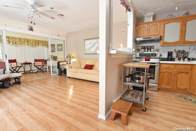 kitchen featuring stainless steel range, decorative backsplash, light wood-type flooring, and ceiling fan