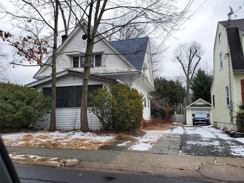 view of front of property with a sunroom, a garage, and an outdoor structure