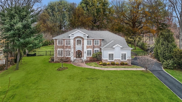 view of front of property with driveway, a front yard, stone siding, stucco siding, and fence
