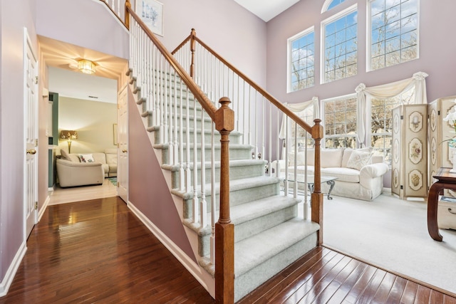 staircase with a high ceiling and hardwood / wood-style floors