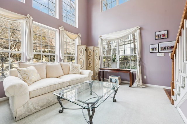 carpeted living room with a towering ceiling and plenty of natural light