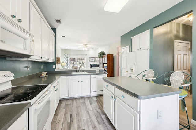 kitchen featuring white appliances, white cabinets, a center island, sink, and ceiling fan