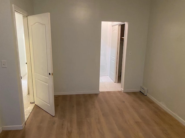 unfurnished room featuring a baseboard radiator and light hardwood / wood-style floors