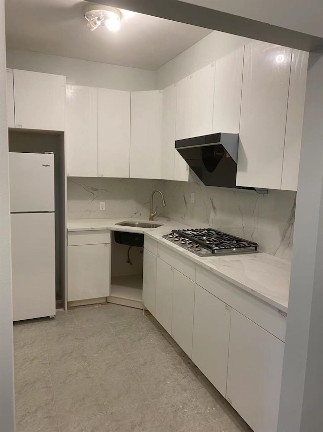 kitchen featuring white cabinets, white refrigerator, stainless steel gas stovetop, and sink