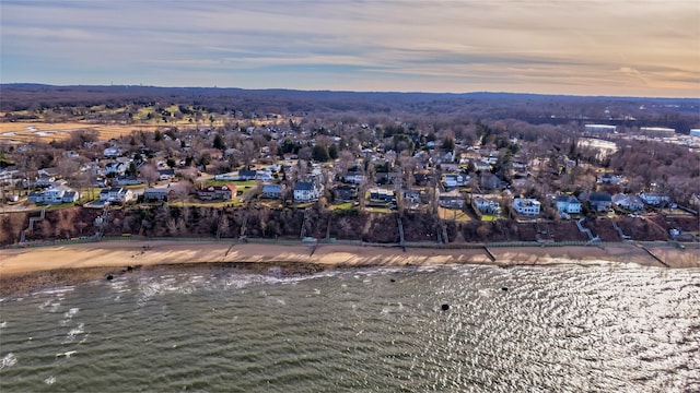 aerial view at dusk with a water view and a view of the beach