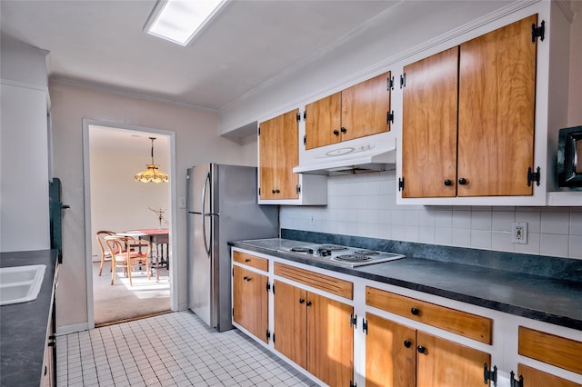 kitchen with sink, decorative backsplash, stainless steel refrigerator, and electric cooktop