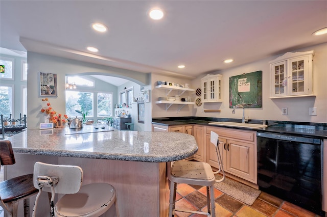 kitchen with sink, black appliances, a breakfast bar, and dark stone countertops