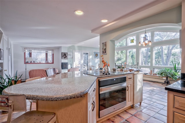 kitchen featuring an inviting chandelier, an island with sink, appliances with stainless steel finishes, french doors, and a breakfast bar