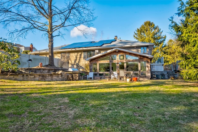 back of house featuring a yard, a sunroom, solar panels, and a patio