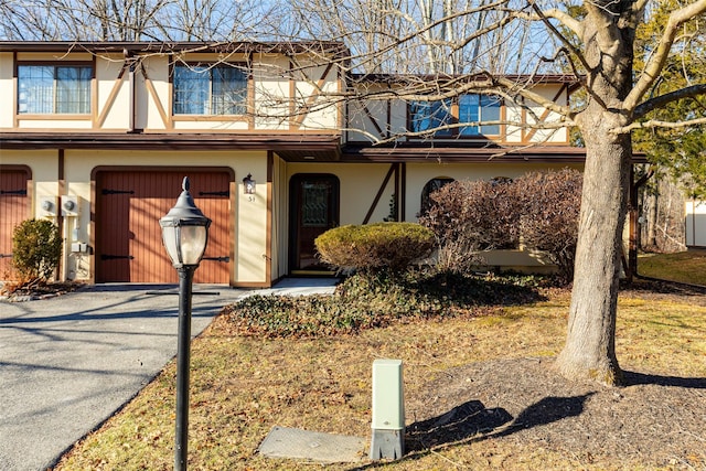 view of property featuring aphalt driveway, a garage, and stucco siding