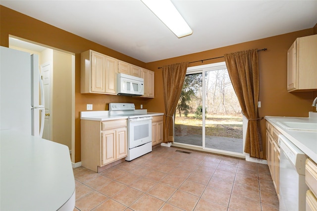 kitchen featuring light tile patterned floors, white appliances, and sink