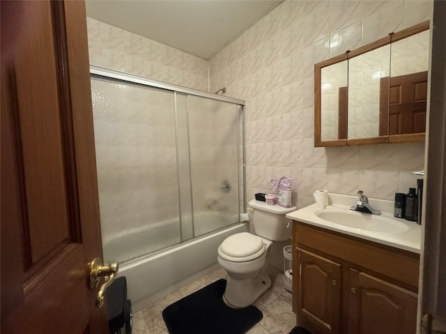 full bathroom featuring toilet, vanity, tile walls, and bath / shower combo with glass door