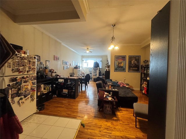 dining area featuring light hardwood / wood-style flooring, crown molding, and ceiling fan with notable chandelier