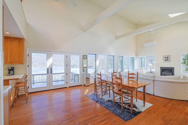 dining area featuring a wall mounted AC, a skylight, light hardwood / wood-style flooring, ceiling fan, and a healthy amount of sunlight