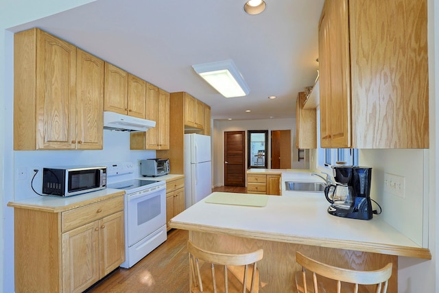 kitchen featuring a breakfast bar, sink, light brown cabinets, kitchen peninsula, and white appliances