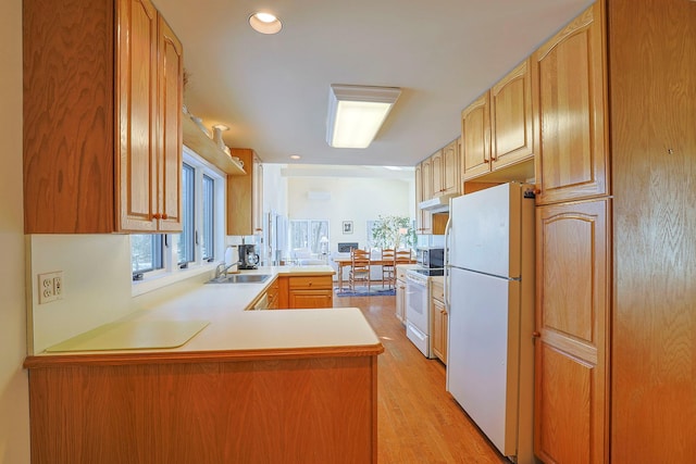 kitchen featuring white appliances, sink, kitchen peninsula, and light hardwood / wood-style floors