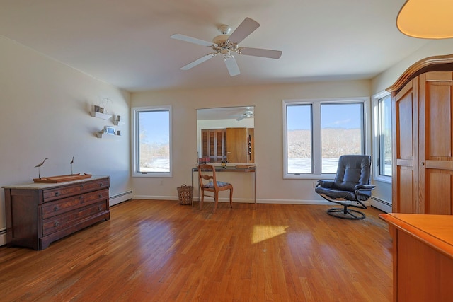 sitting room featuring a healthy amount of sunlight, light hardwood / wood-style floors, and a baseboard heating unit