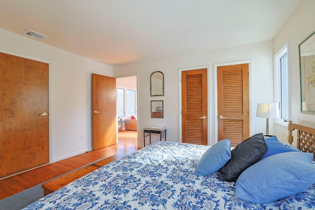 bedroom featuring hardwood / wood-style floors and two closets