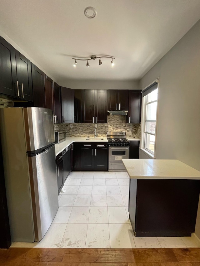 kitchen featuring light tile patterned floors, appliances with stainless steel finishes, backsplash, dark brown cabinetry, and sink