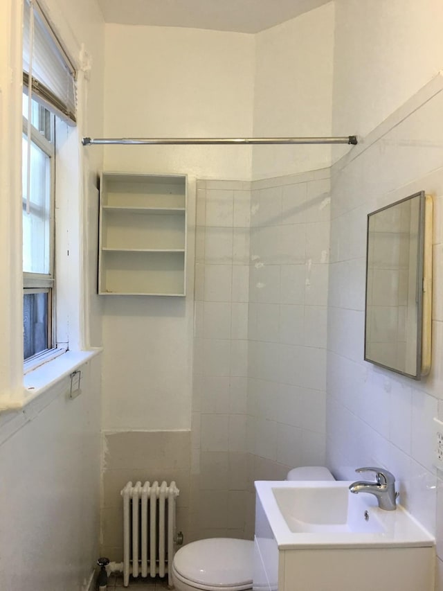 bathroom with radiator, sink, backsplash, tile walls, and toilet