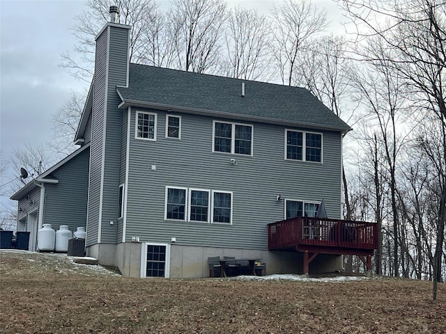 rear view of property featuring a garage and a deck