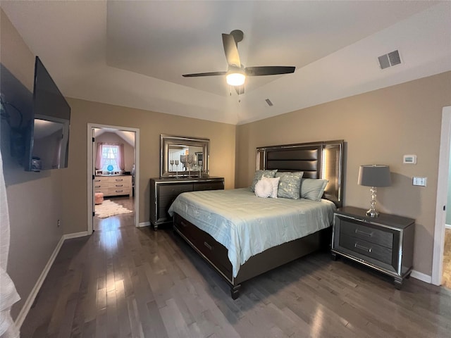 bedroom with dark hardwood / wood-style floors, ceiling fan, and a raised ceiling