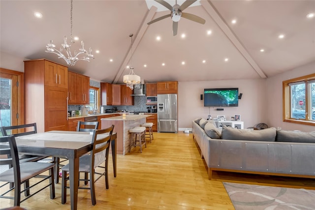 interior space with light wood-type flooring, plenty of natural light, beamed ceiling, and ceiling fan with notable chandelier