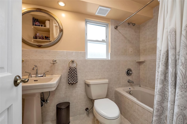 bathroom with toilet, shower / tub combo, and tile walls