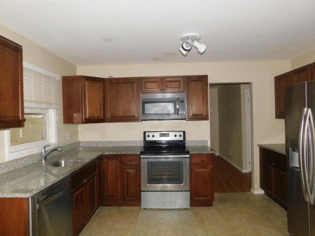 kitchen with light stone counters, sink, and stainless steel appliances