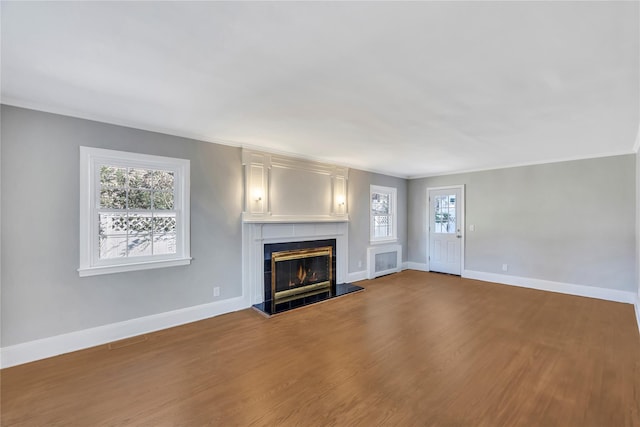 unfurnished living room featuring hardwood / wood-style floors, crown molding, a fireplace, and a healthy amount of sunlight