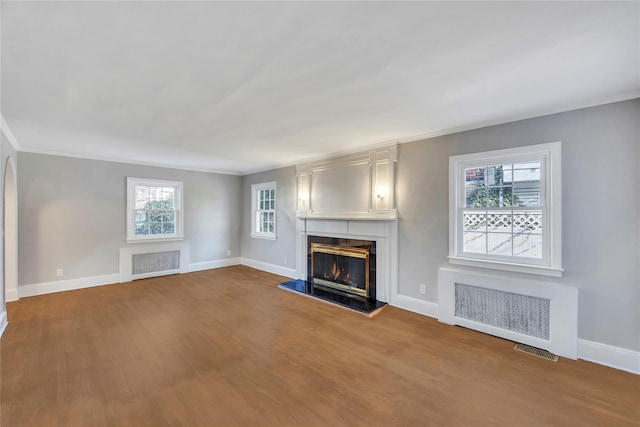 unfurnished living room with radiator heating unit, crown molding, and hardwood / wood-style floors