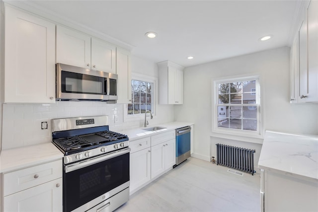 kitchen featuring white cabinets, sink, stainless steel appliances, and radiator