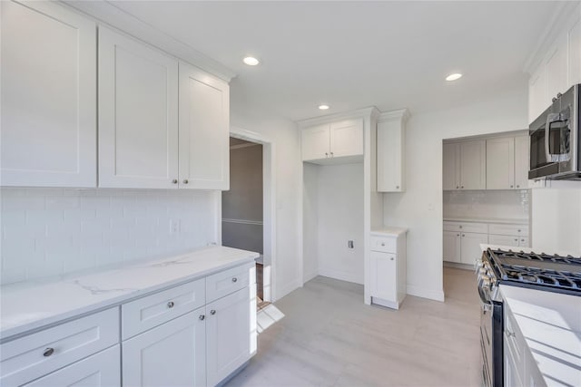 kitchen with decorative backsplash, white cabinetry, and appliances with stainless steel finishes