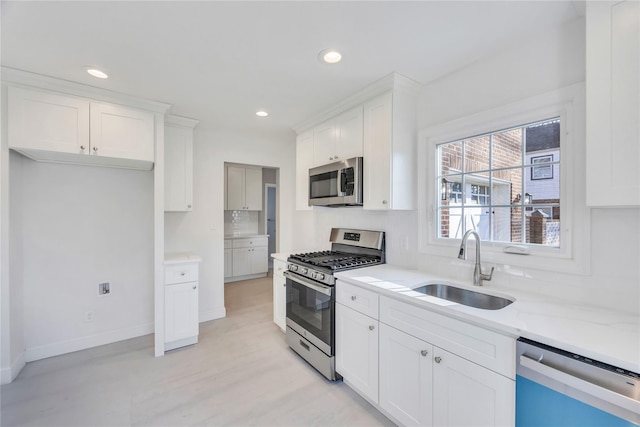 kitchen featuring light stone countertops, appliances with stainless steel finishes, white cabinetry, and sink