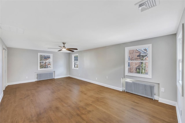 unfurnished living room with radiator heating unit, ceiling fan, and hardwood / wood-style floors