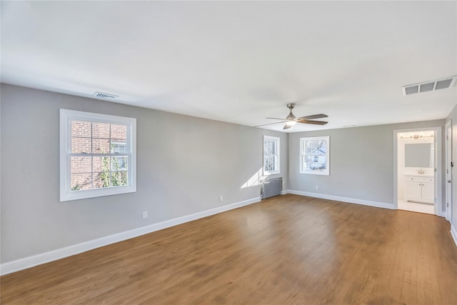 unfurnished room with ceiling fan, wood-type flooring, and radiator heating unit