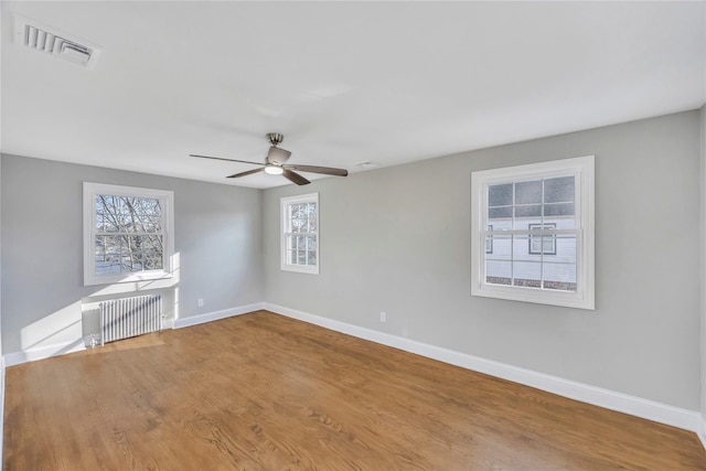 empty room featuring radiator heating unit, ceiling fan, and wood-type flooring