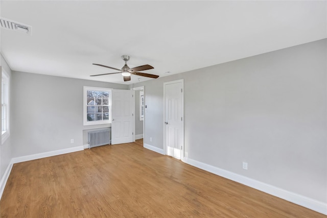 spare room featuring ceiling fan, radiator heating unit, and light hardwood / wood-style flooring