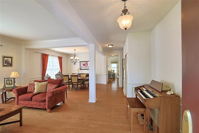 living room with a chandelier, light hardwood / wood-style flooring, and crown molding