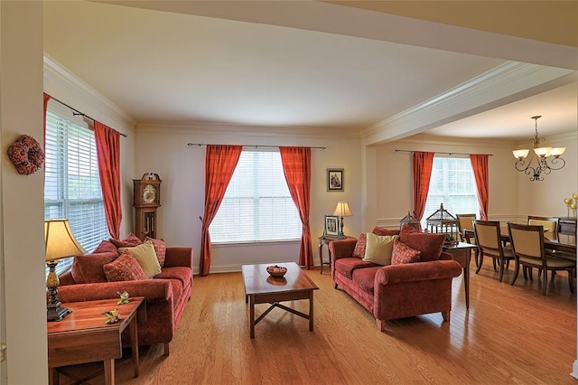 living room featuring a healthy amount of sunlight, crown molding, light hardwood / wood-style floors, and an inviting chandelier