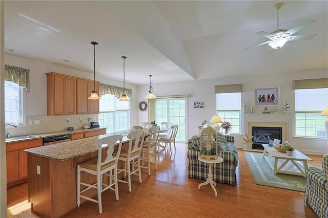 kitchen with ceiling fan, dishwasher, sink, lofted ceiling, and a kitchen bar