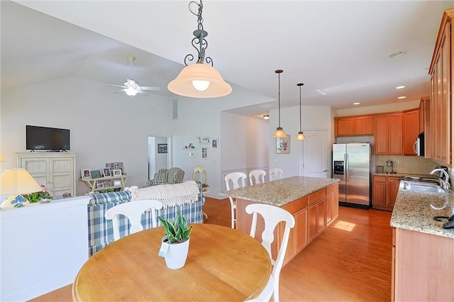 dining room with ceiling fan, sink, vaulted ceiling, and light hardwood / wood-style flooring