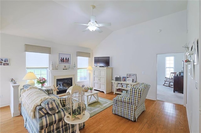 living room featuring ceiling fan, vaulted ceiling, and light hardwood / wood-style flooring