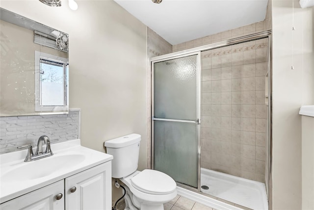 bathroom featuring a stall shower, toilet, tile patterned flooring, vanity, and backsplash