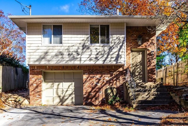 view of front of home with aphalt driveway, brick siding, fence, and a garage