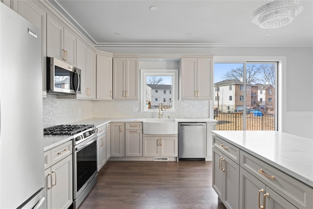 kitchen featuring stainless steel appliances, sink, pendant lighting, a chandelier, and dark hardwood / wood-style floors